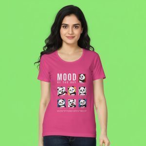 A woman wearing a bright pink T-shirt with multiple cartoon panda faces showing different moods for each day of the week. The text on the shirt reads “Mood of the Day – Have a Pandatastic Week.” She stands smiling against a green background.